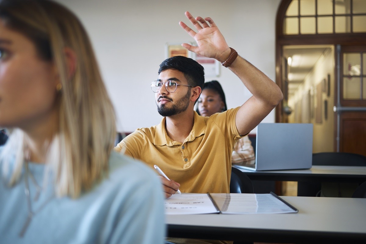 A male student raises a hand to ask a question in class