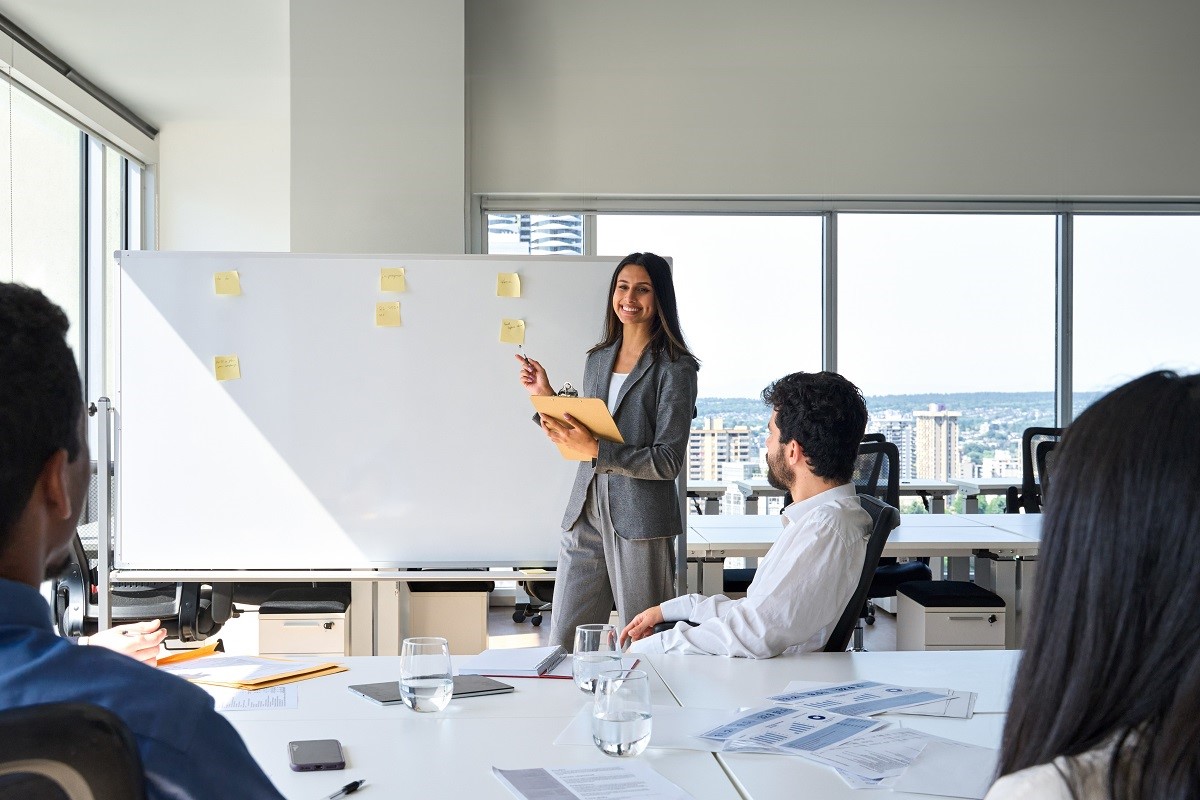 A young professional uses a whiteboard to present to colleagues