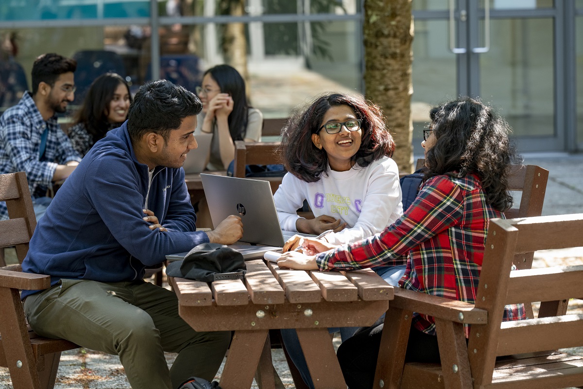 Students sat outside working at a laptop